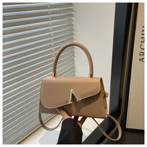 Detail of light brown crossbody bag with gold V hardware and detachable shoulder strap