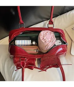 Spacious interior of red glossy bow shoulder bag holding a wallet and folding umbrella