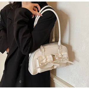 Close-up of cream bow shoulder bag on black blazer showing retro sweet design details