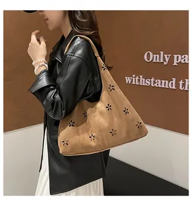 Detailed close-up of brown suede tote bag with laser-cut floral hollow patterns