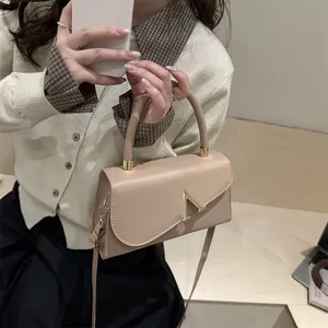 Elegant beige leather handbag with gold V buckle and adjustable strap for women