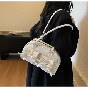 Detail of white shoulder bag featuring bow pockets and silver metal hardware accents