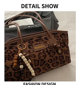 Detalle del bolso tote de leopardo en antelina con parche FASHION y borla de cuentas
