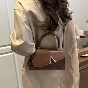 Elegant dark brown leather handbag with golden V-clasp and circular handle for women