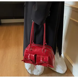 Detail of red patent leather shoulder bag with decorative bows and front pockets