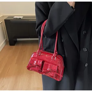 Detail of red patent leather shoulder bag featuring bow pockets and glossy texture