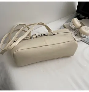 Détail de la texture en cuir PU crème et de la boucle en métal sur le sac à bandoulière chic