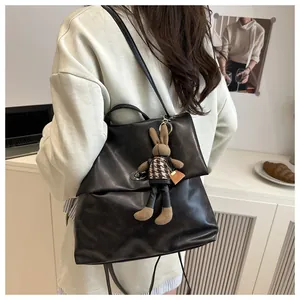 Detail of black faux leather backpack featuring a metal twist lock and a cute bunny charm