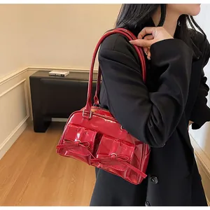 Detail of red glossy patent leather shoulder bag featuring decorative front bows