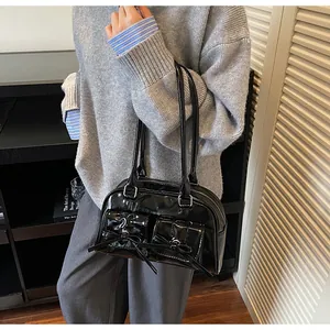 Detail of black patent leather shoulder bag with decorative bows and silver hardware