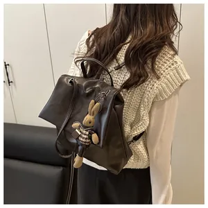 Detailed back view of a minimalist deep brown leather backpack with a cute bunny charm