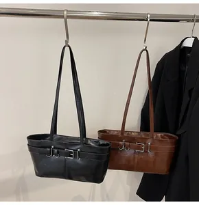Détail de sacs bandoulière minimalistes en noir et marron avec boucles décoratives