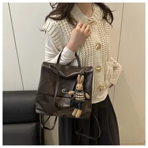 Detail of dark brown tote bag featuring a metallic swivel lock and a cute rabbit plush charm