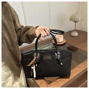 Detalle de bolso tote de ante negro con etiqueta de moda y borla de cuentas de madera