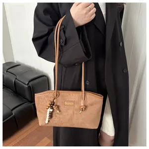 Detalle del bolso tote vintage de ante marrón con logo fashion y borla de cuentas de madera