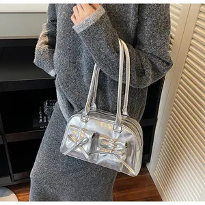 Detail of silver metallic handbag with bow pockets worn as an underarm shoulder bag