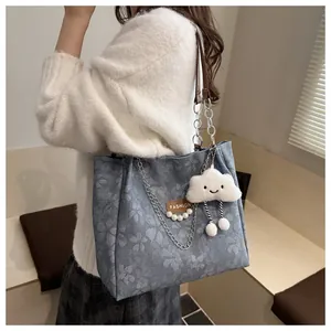 Detalle de bolso tote floral azul claro con cadena, asa de cuero y colgante nube