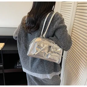 Detail of silver metallic shoulder bag with bow pockets shown on model for sizing
