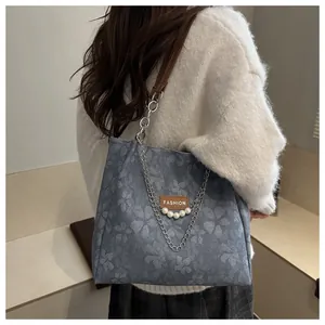 Detalle de bolso tote jacquard con cadena de perlas y correas de cuero marrón
