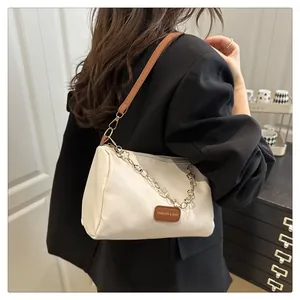 Détail du sac crème avec chaîne à fleurs dorées porté sur un blazer noir élégant