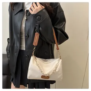 Détail du sac oreiller blanc crème avec chaîne pétale dorée et étiquette en cuir