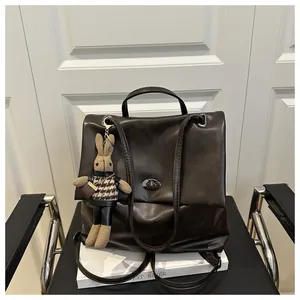 Detailed view of deep brown leather backpack with metal turn-lock and knit bunny charm