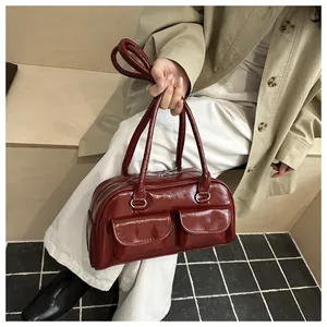Close-up of a glossy burgundy underarm bag with silver hardware and front pocket details