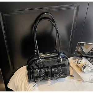 Close-up of black patent leather underarm bag featuring dual bow pockets and glossy finish