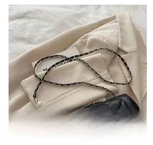 Détail du sac matelassé noir avec bandoulière composée de perles et de chaîne dorée