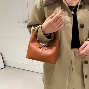 Minimalist tan leather handbag with semi-circular design and dual zippers in interior setting