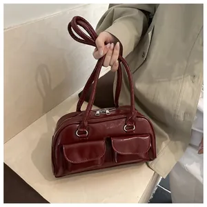 Detail of wine red patent leather shoulder bag with glossy finish and front pockets