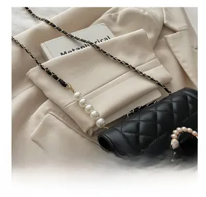 Détail d'un sac matelassé noir avec chaîne en perles et boucle ronde ornée de perles