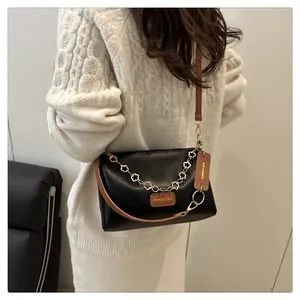 Détail du sac bandoulière noir avec chaîne florale dorée et étiquettes en cuir marron