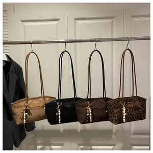 Vista detallada de bolsos tote de ante en varios colores con colgantes de cuentas