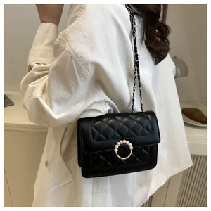 Détail du sac matelassé noir avec boucle élégante ornée de perles et bandoulière en cuir