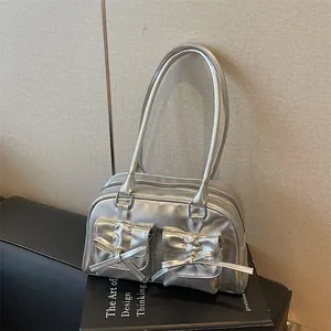 Chic silver metallic underarm bag with bow-knot details on a minimalist book background