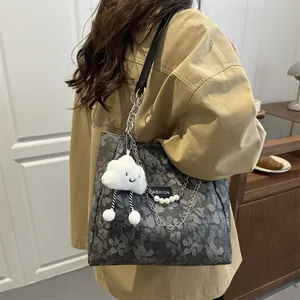 Bolso tote gris con flores, cadena de perlas y etiqueta de moda en un café