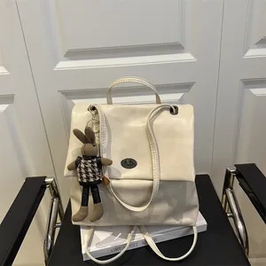 Minimalist beige PU leather tote backpack with a rabbit pendant and turn-lock closure