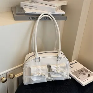 Chic white bow shoulder bag with glossy finish and twin pockets in a minimalist setting