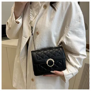 Détail d'un sac noir matelassé avec boucle en perles et bandoulière chaîne perlée