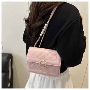 Gros plan d'un sac à bandoulière matelassé rose avec boucle perle et chaîne dorée