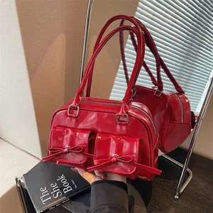 Glossy red patent leather underarm bag with double bow pockets in mirror reflection view