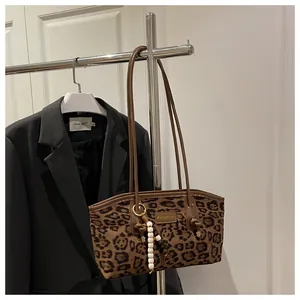 Detalle de bolso tote de ante con estampado de leopardo, placa dorada y adorno de cuentas