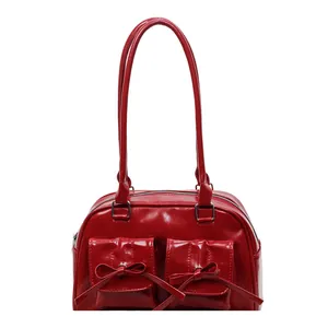 Red patent leather Y2K shoulder bag with bow details and twin pockets on white background