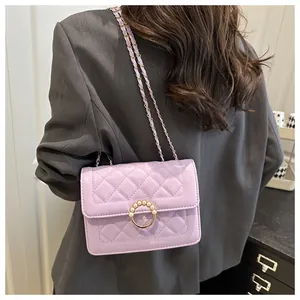 Détail du sac matelassé violet clair avec boucle perle dorée sur un blazer gris