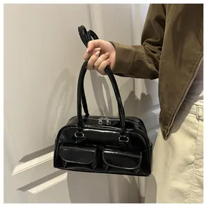 Detail of black glossy patent leather shoulder bag with dual front flap pockets