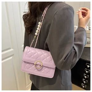 Détail d'un sac bandoulière matelassé lavande avec perles et boucle métallique circulaire