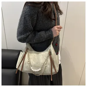 Detalle de bolso tote mate verde grisáceo con cadenas de perlas y correa de cuero