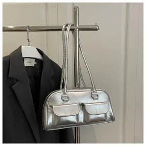Close-up of metallic silver underarm bag with double square pockets on a hanger