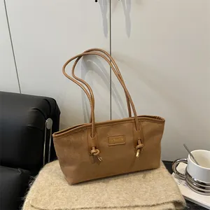 Bolso tote vintage de ante marrón con correas de cuero sobre un fondo de punto suave